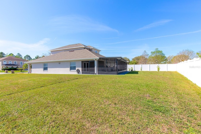 rear view of house featuring a sunroom, a fenced backyard, a yard, and stucco siding