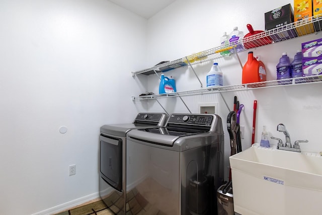 washroom with washer and dryer, laundry area, a sink, and baseboards