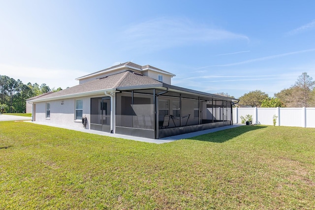 rear view of house featuring a lawn, fence, and a sunroom