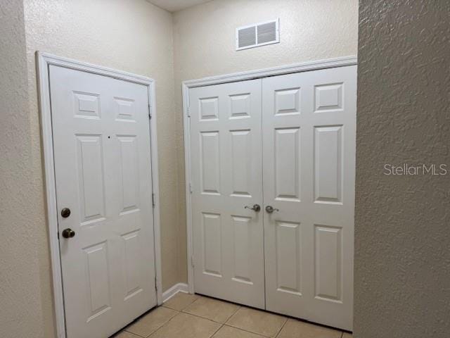 foyer featuring light tile patterned flooring, visible vents, and a textured wall