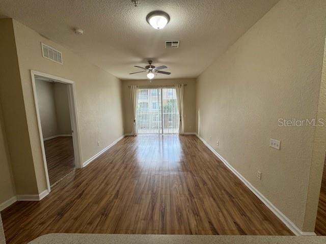 unfurnished room with visible vents, a textured ceiling, a ceiling fan, and wood finished floors