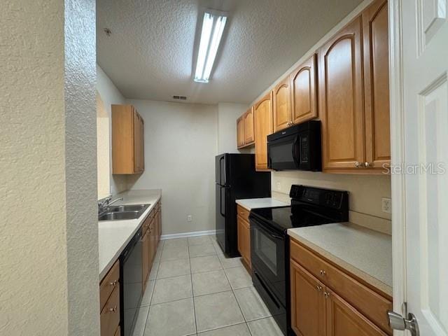 kitchen with a sink, a textured ceiling, black appliances, and light countertops
