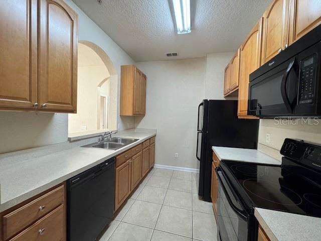 kitchen with visible vents, black appliances, a sink, a textured ceiling, and light countertops