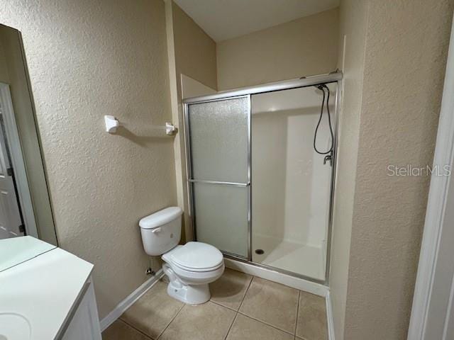 full bathroom featuring tile patterned flooring, toilet, a textured wall, and a stall shower