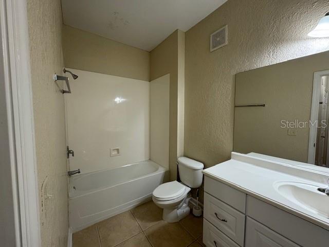 full bathroom with tile patterned floors, visible vents, vanity, and a textured wall