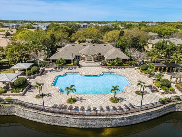 community pool with a patio, a water view, and fence