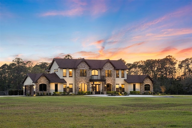 french country inspired facade featuring a balcony and a yard