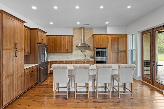 5500 State Road 33, Clermont, FL 34714 - kitchen with stainless steel appliances, wall chimney range hood, brown cabinetry, and a kitchen breakfast bar