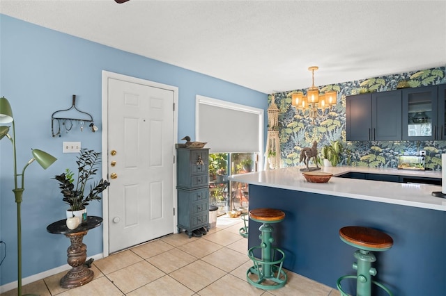 kitchen featuring a breakfast bar area, light tile patterned floors, light countertops, hanging light fixtures, and glass insert cabinets