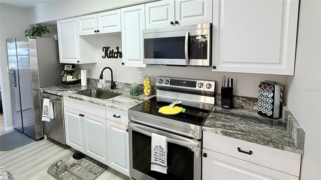 1420 Continental Dr, Daytona Beach, FL 32117 - kitchen featuring stainless steel appliances, a sink, light wood-type flooring, and white cabinetry