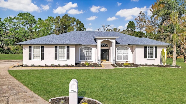 single story home featuring a front lawn, roof with shingles, and stucco siding