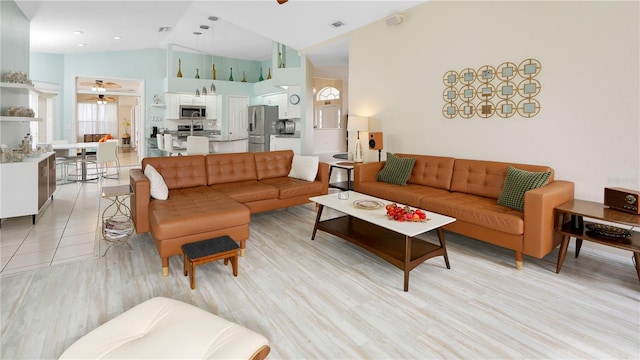 living area featuring visible vents, high vaulted ceiling, light wood-type flooring, and a ceiling fan