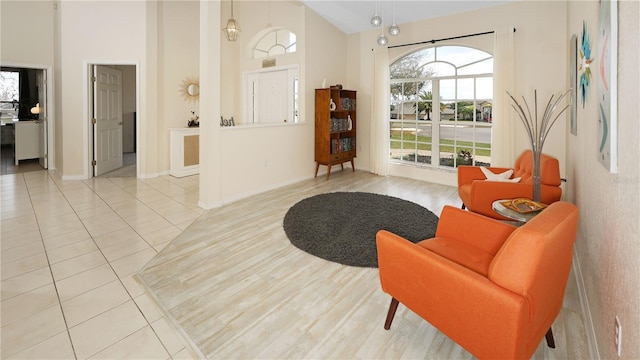 living area with tile patterned floors, high vaulted ceiling, and baseboards