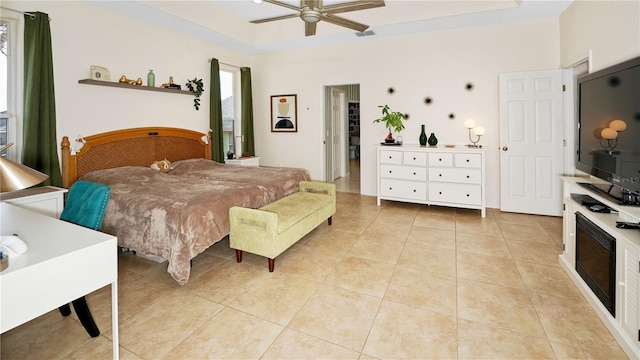 bedroom featuring light tile patterned flooring, visible vents, a raised ceiling, and ceiling fan