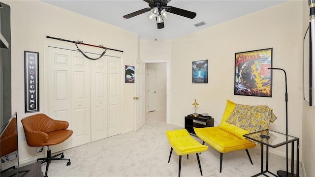 living area with visible vents, carpet, and a ceiling fan