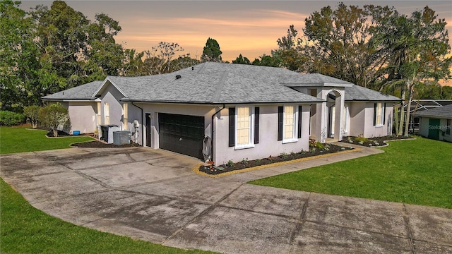 single story home with a garage, stucco siding, driveway, and a yard