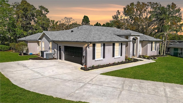 ranch-style house featuring stucco siding, driveway, a lawn, and an attached garage