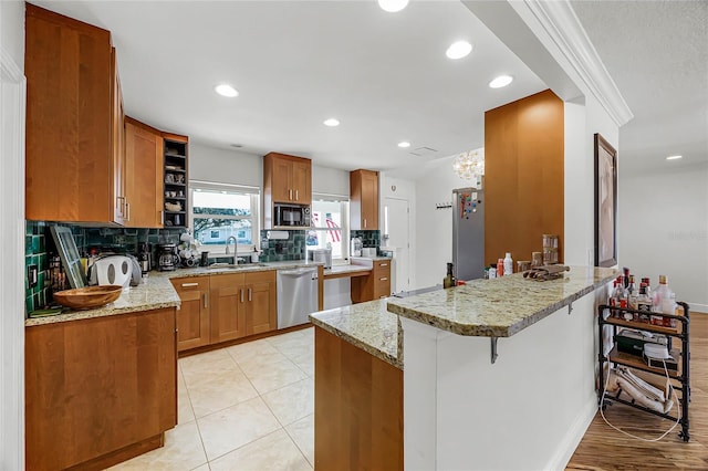 kitchen with dishwasher, brown cabinets, a peninsula, black microwave, and a sink