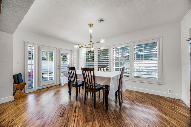 dining room featuring baseboards, visible vents, wood finished floors, a textured ceiling, and a notable chandelier