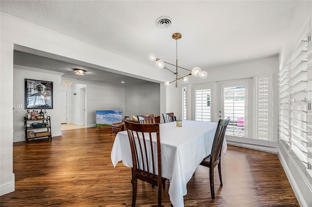 dining space featuring a textured ceiling, a chandelier, visible vents, baseboards, and dark wood-style floors