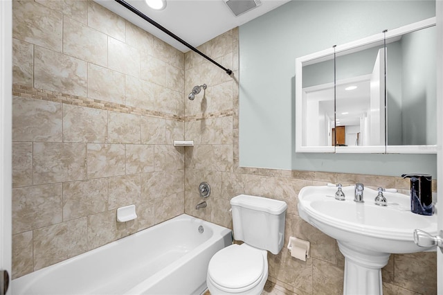 bathroom featuring visible vents, tile walls, toilet, and bathing tub / shower combination