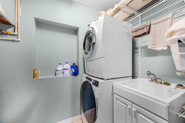 washroom featuring cabinet space, a sink, and stacked washing maching and dryer