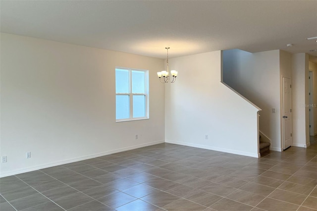 spare room featuring baseboards, an inviting chandelier, and stairs