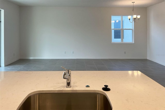 kitchen featuring pendant lighting, a sink, a chandelier, baseboards, and tile patterned floors