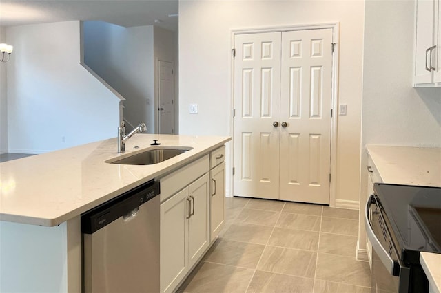 kitchen with light stone counters, white cabinets, a sink, and stainless steel dishwasher