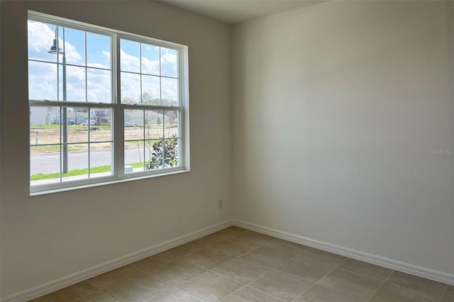 unfurnished room with light tile patterned flooring and baseboards