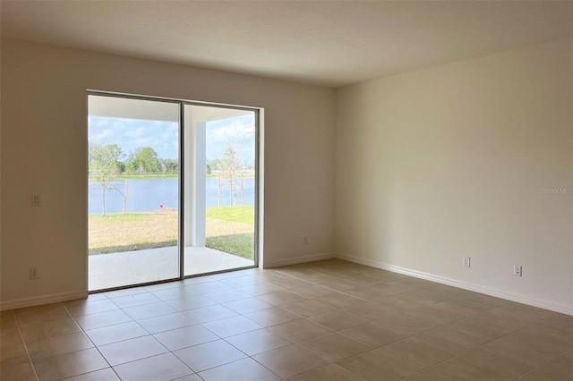 tiled empty room with a water view and baseboards