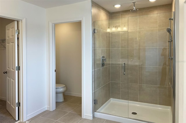 full bath featuring toilet, a shower stall, baseboards, and tile patterned floors