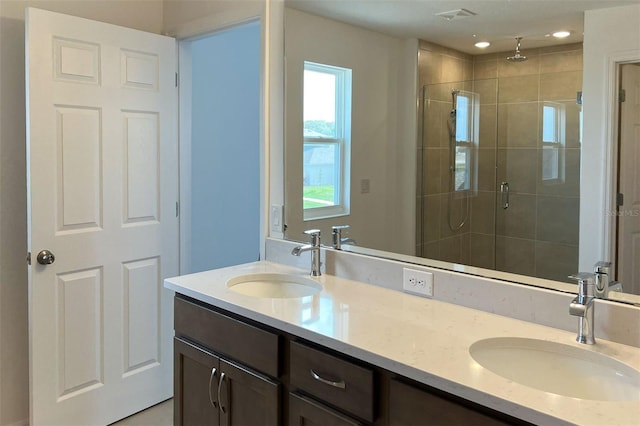 bathroom with a stall shower, visible vents, a sink, and double vanity