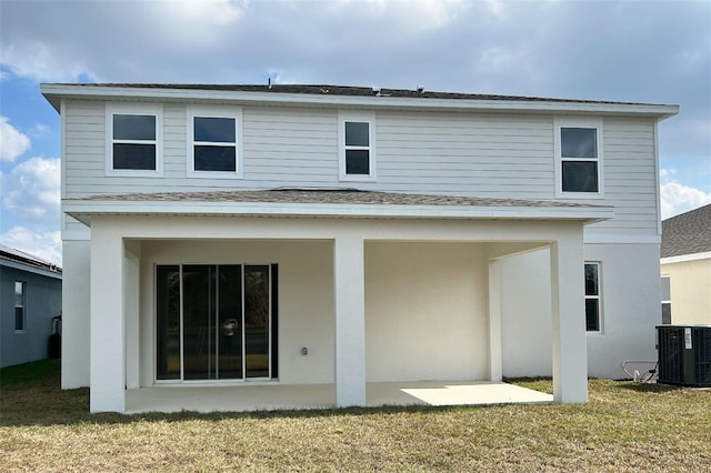 rear view of property featuring central AC, a lawn, roof with shingles, and stucco siding