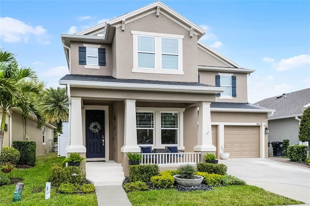 traditional-style home featuring stucco siding, a garage, covered porch, and concrete driveway