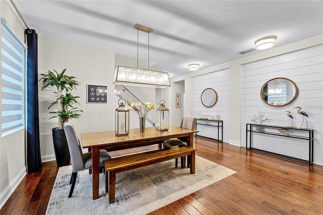 dining area with baseboards, a textured ceiling, and hardwood / wood-style floors