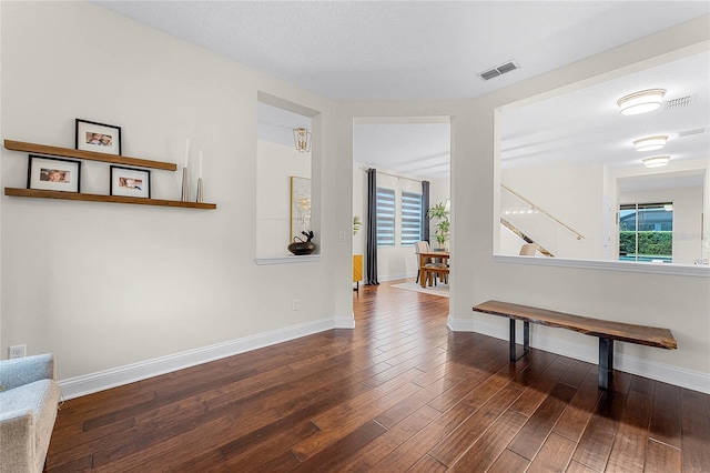 corridor featuring a wealth of natural light, visible vents, baseboards, and wood finished floors