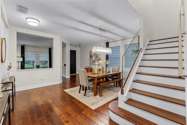 dining area with dark wood finished floors, visible vents, a textured ceiling, and stairs