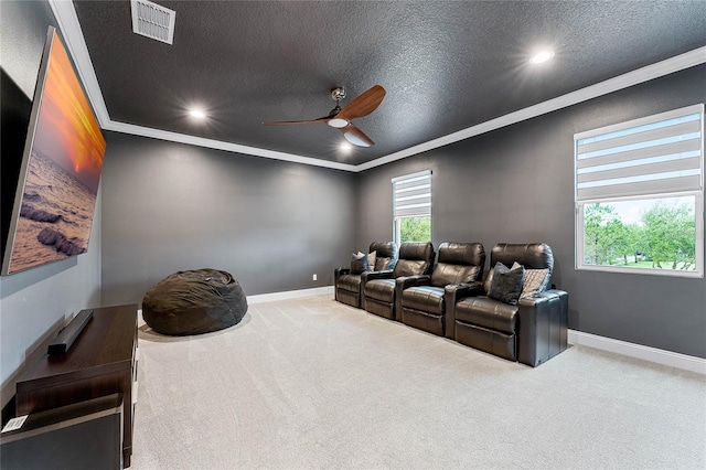 carpeted home theater with a textured ceiling, ceiling fan, visible vents, and ornamental molding