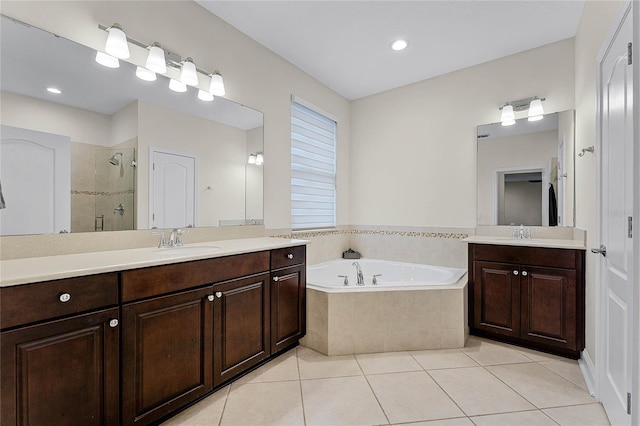 full bath with tile patterned flooring, a shower stall, a garden tub, two vanities, and a sink