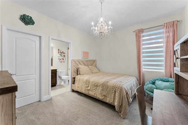 bedroom featuring a notable chandelier, light carpet, a textured ceiling, and ensuite bath