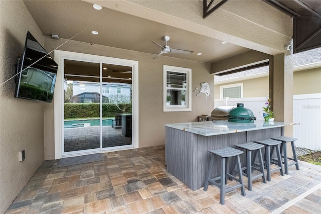 view of patio / terrace with an outdoor kitchen, outdoor wet bar, a ceiling fan, and fence