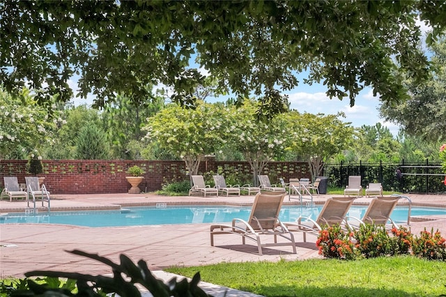 community pool with a patio area and fence