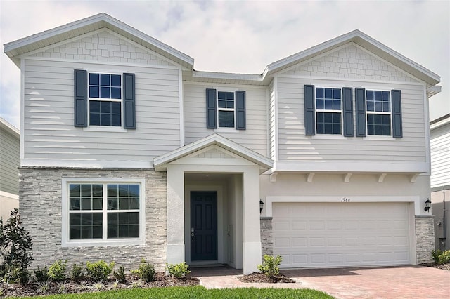 craftsman-style house with an attached garage, stone siding, and decorative driveway