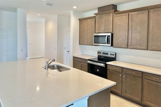 kitchen featuring tasteful backsplash, visible vents, light stone countertops, stainless steel appliances, and a sink