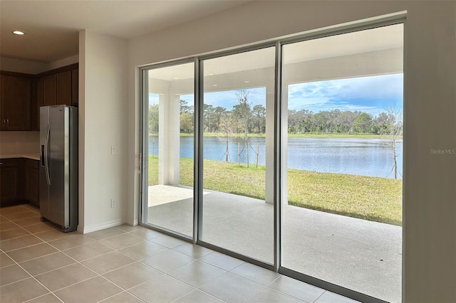 doorway featuring light tile patterned floors, a water view, baseboards, and recessed lighting