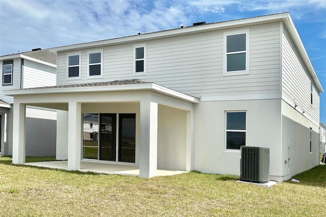 back of property with central air condition unit, a patio, a lawn, and stucco siding