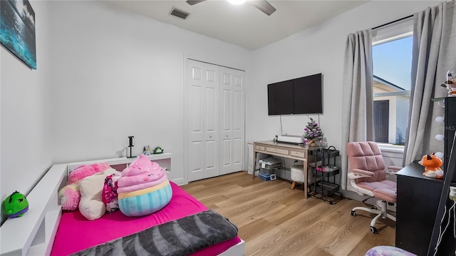 bedroom featuring a ceiling fan, visible vents, light wood-style floors, and a closet