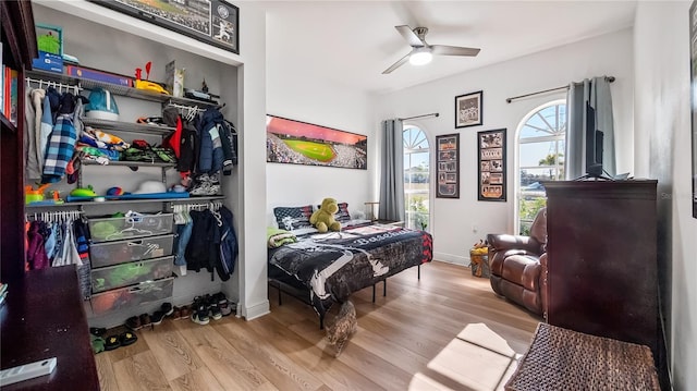 bedroom with a closet, a ceiling fan, baseboards, and wood finished floors