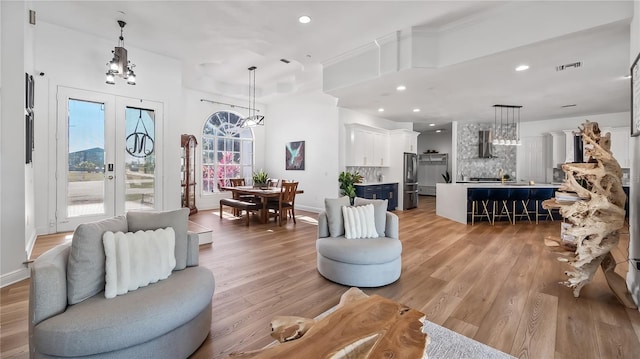 living room featuring light wood finished floors, visible vents, recessed lighting, and french doors